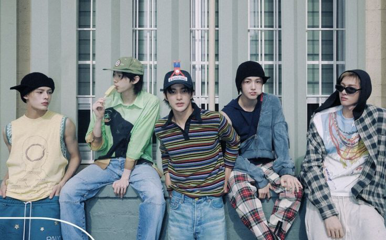 CORTIS members sitting together outside a building