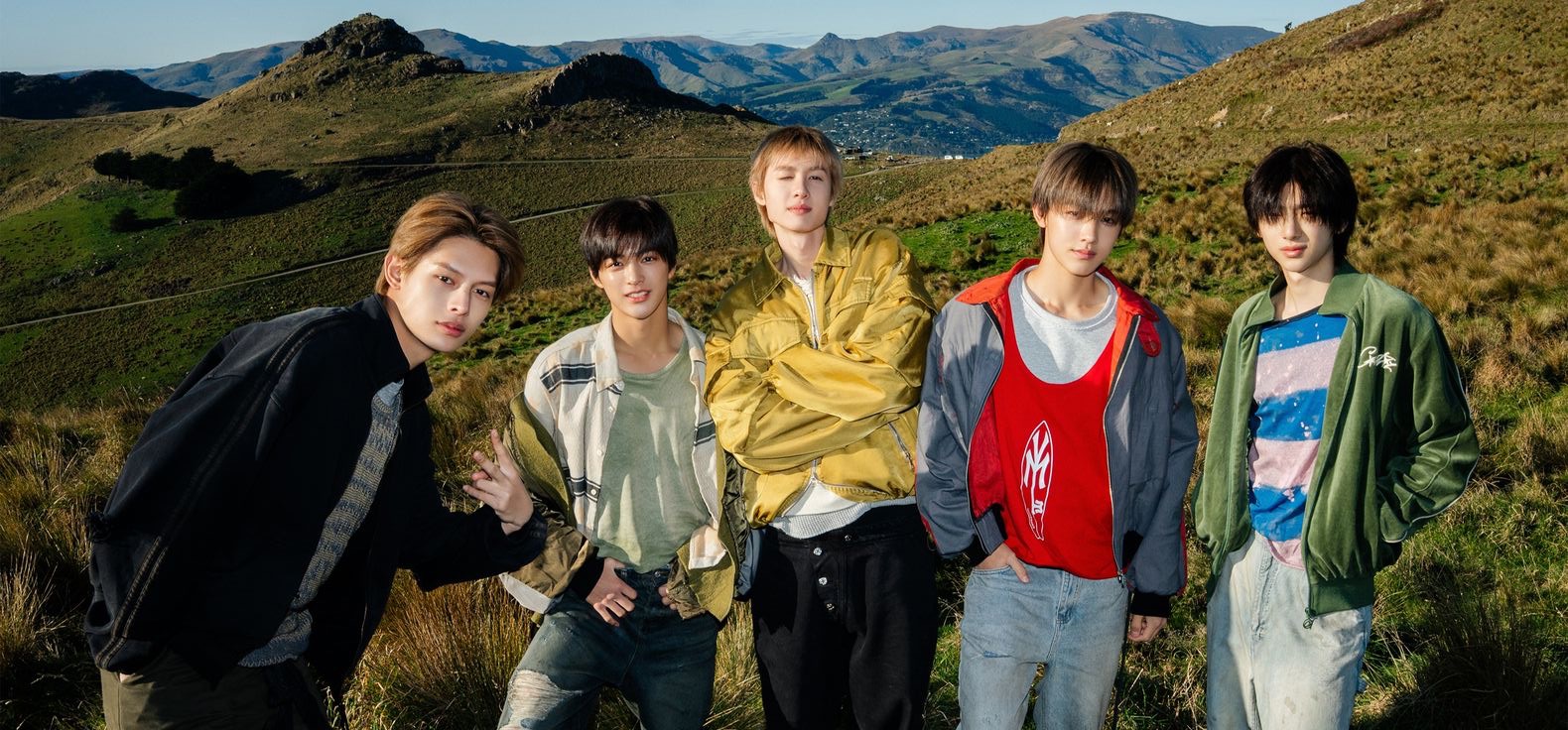 CORTIS members standing together in a mountain landscape